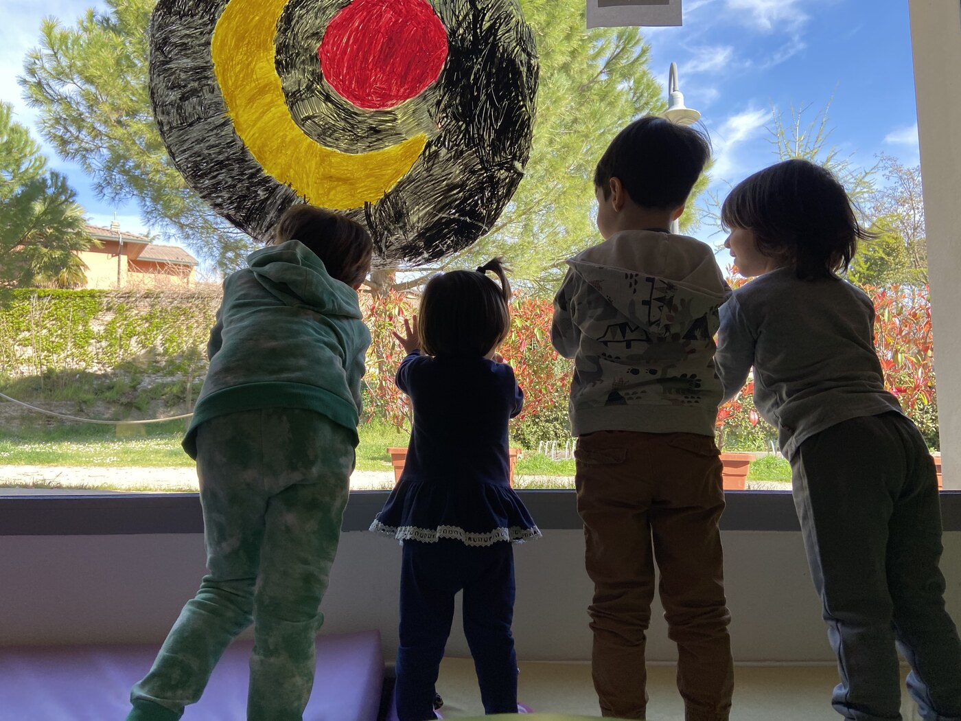 Quattro bambini affacciati alla finestra che guardano il giardino